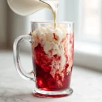 Dirty cherry sprite recipe in a tall glass with cherry syrup, cream, and ice