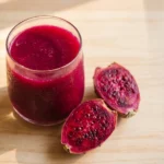 juicing cactus fruit — deep magenta prickly pear juice in a glass with cut fruit alongside