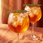 Mocktail aperol spritz in a stemmed wine glass with orange wheel and rosemary sprig