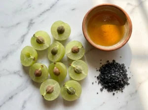 Fresh halved nelli (amla) fruits with raw honey and black salt, key ingredients for nelli fruit juice