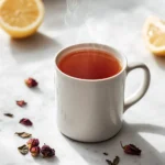 Square close-up of raspberry leaf tea in a white mug with scattered dried leaves on marble
