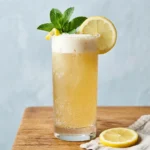 dirty lemonade soda recipe in a tall Collins glass with lemon wheel and mint sprig garnish