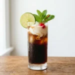 founder dirty soda recipe in tall glass with dark cola cream swirl lime wheel and maraschino cherry garnish