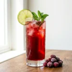 long beach iced tea mocktail in a Collins glass with lime wheel and frozen cranberry garnish