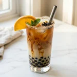 Oolong boba tea in a clear glass with black tapioca pearls, brown sugar swirl, and a wide boba straw on a light wood surface