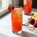 strawberry lemonade mocktail in tall glass with fresh strawberry garnish and lemon slice