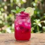 Dragon fruit punch mocktail in a mason jar garnished with lime and mint