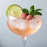 Lychee lime mojito spritz in a coupe glass with lime, lychee and mint garnish