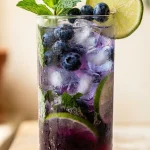 Blueberry mojito recipe in a highball glass with lime and mint garnish