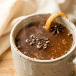 Clove tea recipe in a ceramic mug with cloves and orange peel garnish