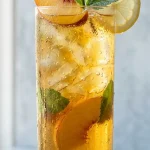 Oolong peach iced tea in a tall glass with peach slice and mint garnish