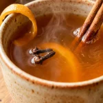Russian tea recipe served hot in a ceramic mug with cinnamon and orange peel