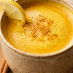 Golden turmeric tea recipe in a ceramic mug with cinnamon and lemon